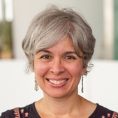 Person with short bobbed grey hair smiles at the camera.